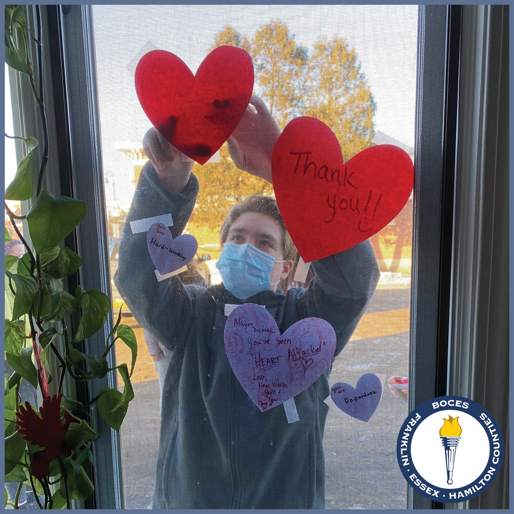 a student tapes hearts to a window