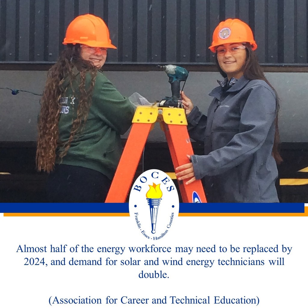 Two female students stand on a ladder using power tools to install lighting outdoors.