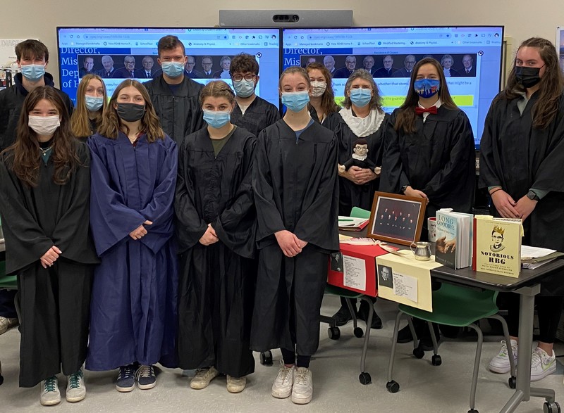 Students dressed in dark gowns pose